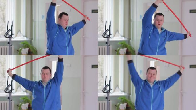 一名患有唐氏综合症的男子用体操棒参加运动，并向健身房的两侧弯曲。