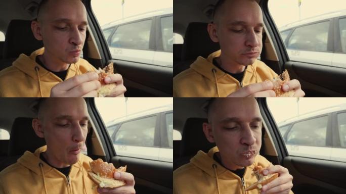 男子司机坐在车里拿着吃快餐店的一个大肉汉堡咬它咀嚼