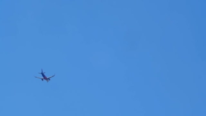 从远处飞行的客机上的地面仰视图。一架小型客机在远处飞过蓝色的万里无云的天空。