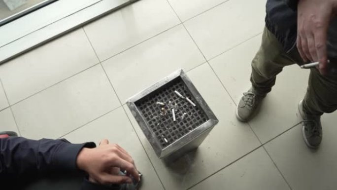 无法识别的男性游客在机场吸烟区吸烟的高角度视图