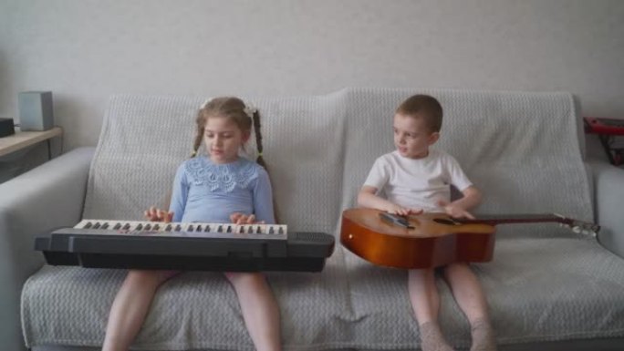 一个可爱的小妹妹和她的哥哥坐在沙发上，吉他。键盘和吉他。兄妹坐在沙发上演奏乐器