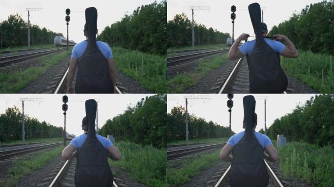 男音乐家沿着铁路铁轨行走，看着离开火车