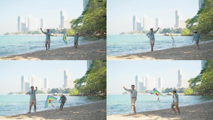 亚洲父亲在沙滩上玩五颜六色的风筝，而他开朗的小儿子则随风飘动着风筝奔跑。他们很开心，有笑脸。假期与家