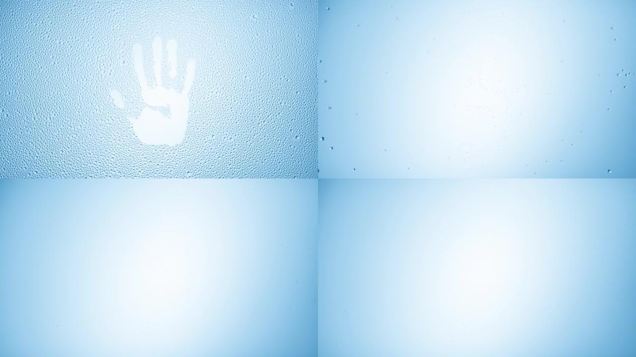 蓝色背景上湿玻璃上的手印吹下来