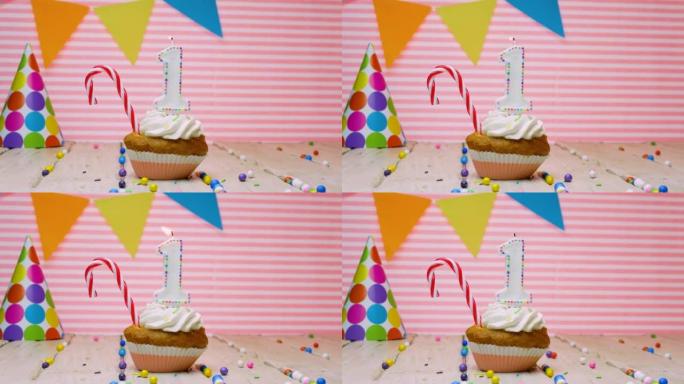 祝1岁的宝宝生日快乐，美丽的快乐生日视频背景1岁在粉红色的背景与奶油纸杯蛋糕和蜡烛与火