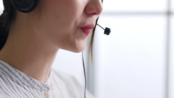 特写亚洲女性呼叫中心，客户服务，穿着正式西装的电话销售，戴着耳机或耳机在办公室与客户交谈