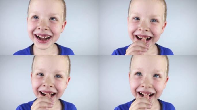 松动的乳牙。金发男孩用手触摸一颗乳牙，展示他是如何移动的。成长的阶段。