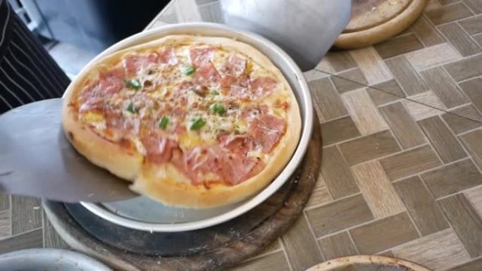 午餐或晚餐的大片热奶酪披萨，夏威夷培根和甜椒酱，木制桌子上的美味意大利快餐。
