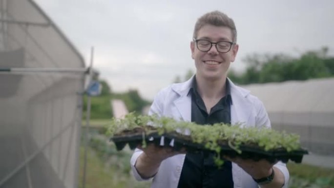 植物研究员抱着一株植物，对着镜头微笑。