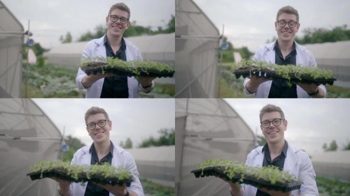 植物研究员抱着一株植物，对着镜头微笑。