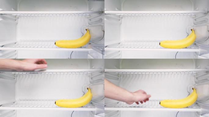 这个人的手打开一个空冰箱，拿走一根香蕉。概念性4k原始视频。经济危机、粮食短缺、贫困的想法。