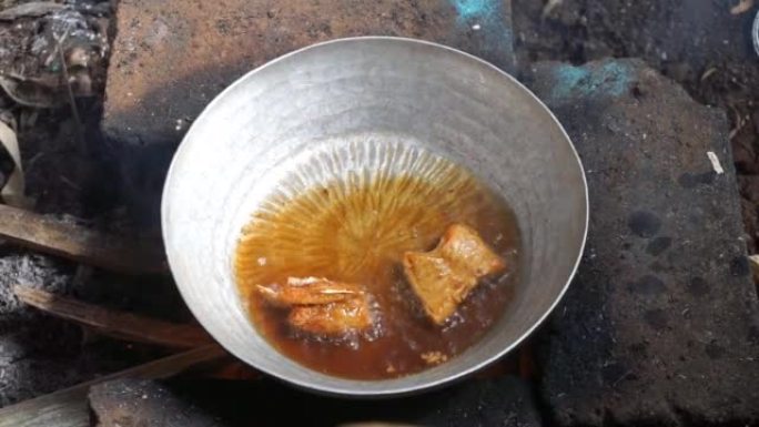 使用传统的燃木炉烹饪咸鱼