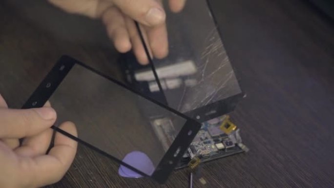手机维修，一名男子拆开智能手机的机身。