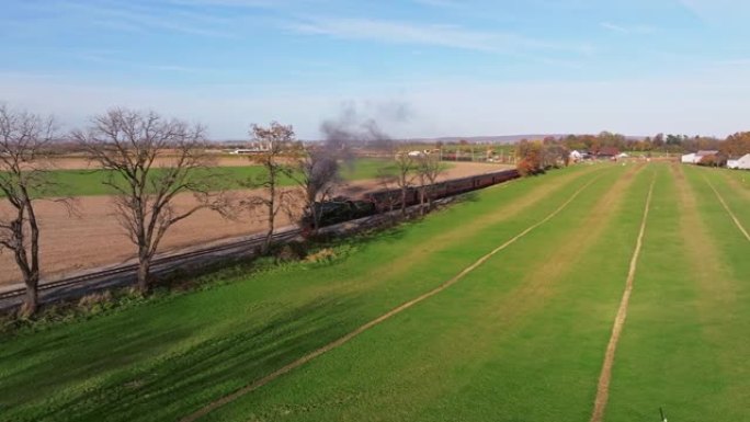 随着蒸汽火车的进近，一条穿过乡村农田的铁路轨道的鸟瞰图