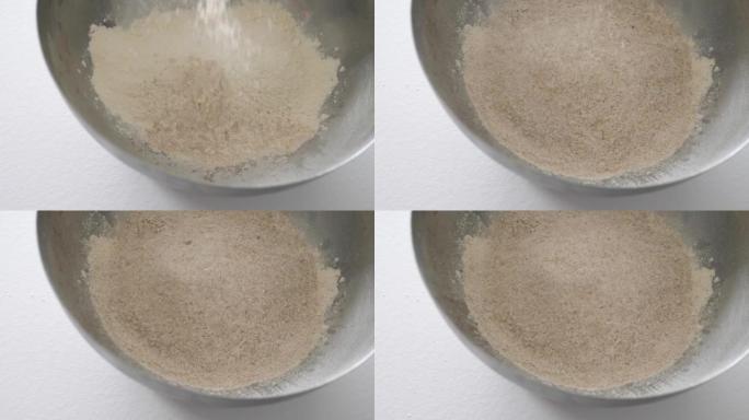 在一个大银碗中向白面粉中添加全麦面粉