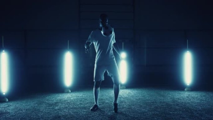 职业足球运动员在黑暗的工作室练习踢球，对抗明亮的拱腹