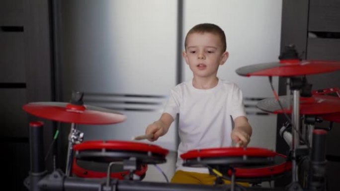 一个男孩在家玩电子鼓。一个小男孩喜欢在家玩电子鼓，红色鼓。在家隔离的男孩练习鼓