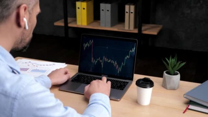 成人股票交易员经纪人在办公室使用带有股票交易图表的笔记本电脑