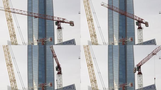 高吊车在带有玻璃建筑塔的建筑工地上工作