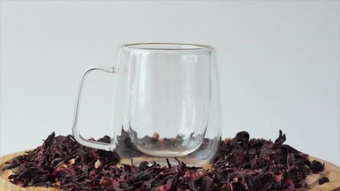 白底玻璃杯中的红茶。将红芙蓉茶倒入带有双壁的透明玻璃中。一杯在木板上旋转的茶。