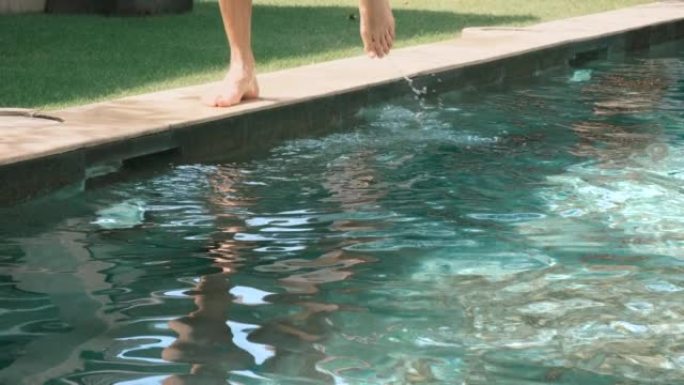 男人的脚在室外游泳池和草坪的背景下。人类踢水和飞溅。在游泳池里训练。4k，慢动作