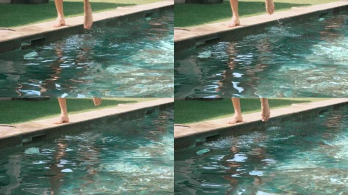 男人的脚在室外游泳池和草坪的背景下。人类踢水和飞溅。在游泳池里训练。4k，慢动作