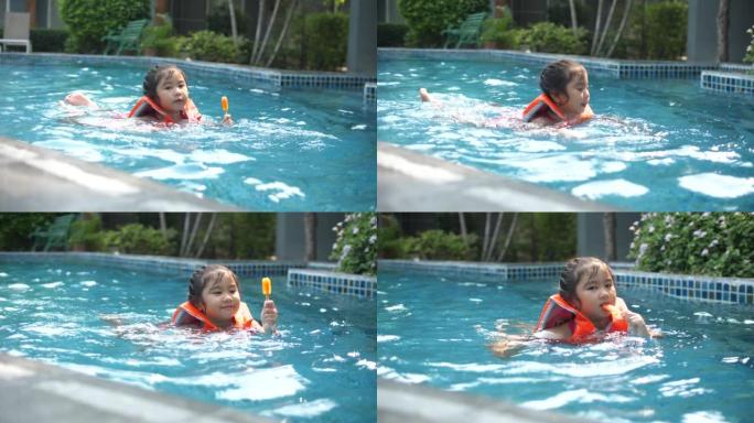 快乐的小女孩在游泳池游泳时吃冰淇淋