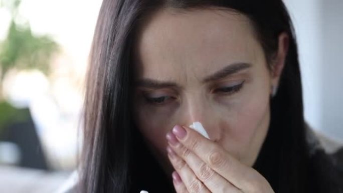 流鼻涕的女人手里拿着药，泡在红鼻子里