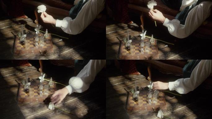 一个人的手拿着一朵白花，放在地板上，用烧瓶下棋。调香师的概念，休息，创意危机，反思。电影概念。特写。
