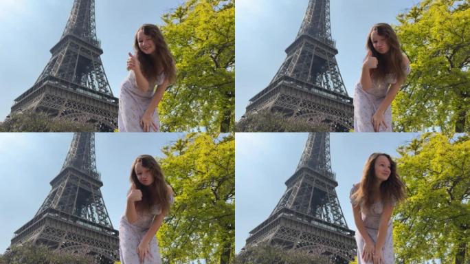 巴黎美丽的年轻少女在埃菲尔铁塔的背景下，穿着一件别致的长裙微笑着，展示了全班学生看着镜头。她留着长长
