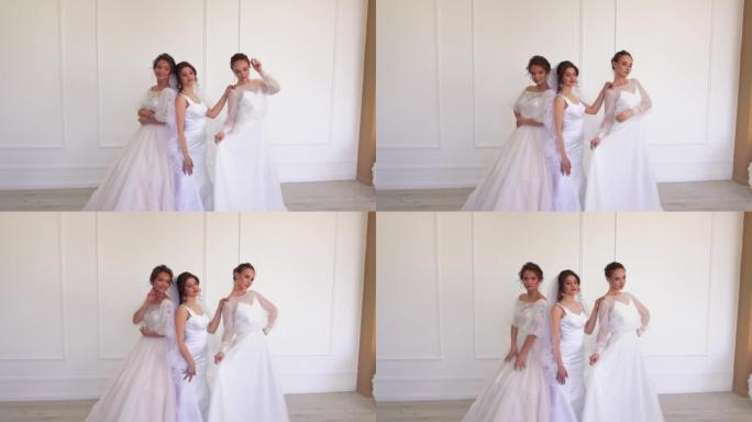三个穿着白色连衣裙的黑发漂亮新娘正站着摆姿势。