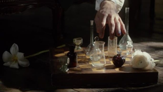 一个人的手在棋盘上用烧瓶下棋。调香师的概念，放松，创意危机，反思，玩耍，发明。电影概念。特写。4k视