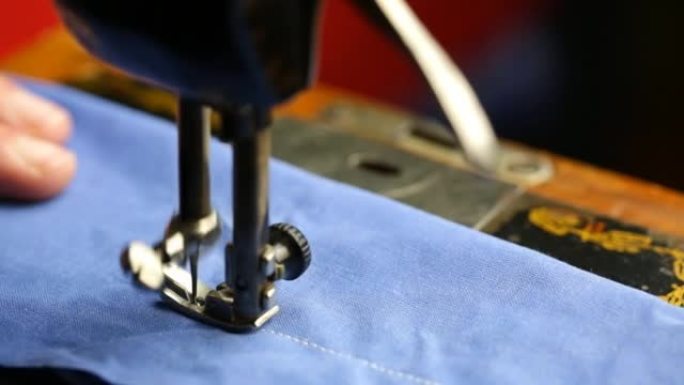 男子在缝纫机上缝制蓝色织物