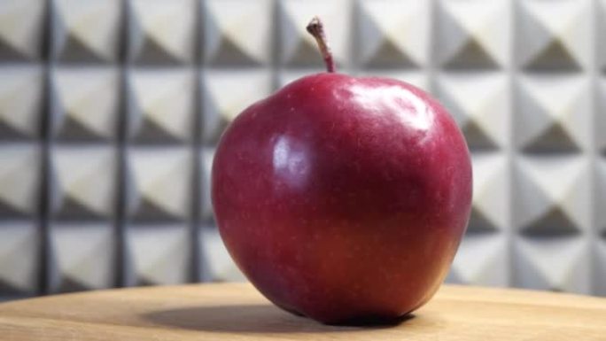 一个红色的苹果在灰色墙壁背景的旋转表面上。视频4k。
