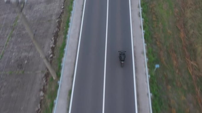 摩托车手在乡村公路上骑摩托车的俯视图。男人在旅行中驾驶自行车。在乡村路线骑现代运动摩托车的自行车手的