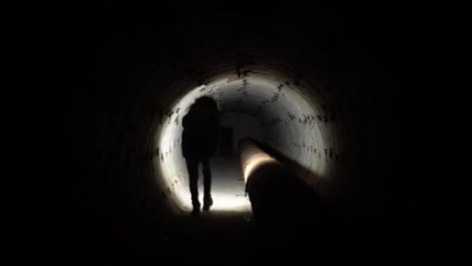 一个人用管道穿过地下通讯隧道。