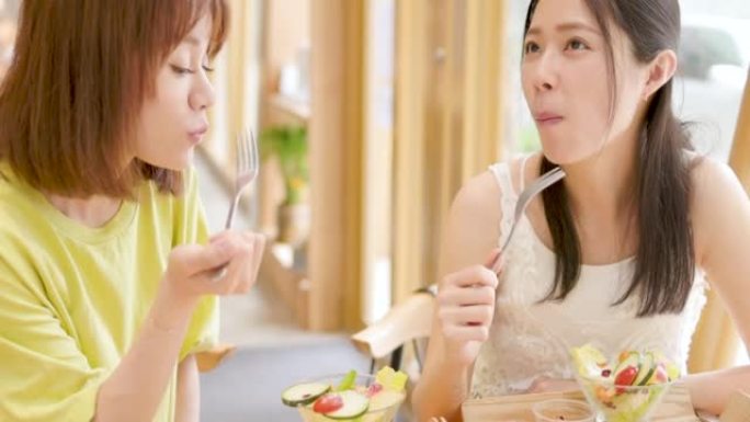 女性朋友在餐厅享受新鲜沙拉，玩得开心。