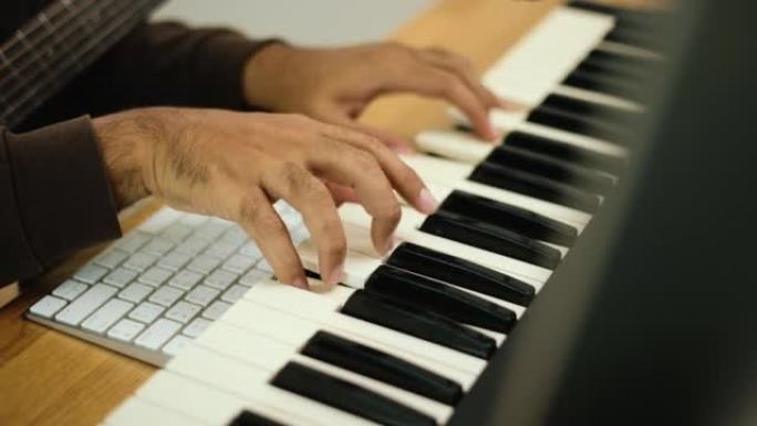 特写手专业歌曲作者用平板电脑弹奏钢琴键盘和吉他，用于混合和掌握音乐。男在录音室用音响设备创作歌曲。音
