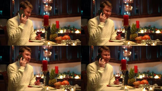 笑着的人坐在餐桌旁，在家里的厨房里吃浪漫的晚餐。积极的白人男友在周年纪念日等待准备惊喜的肖像。浪漫和