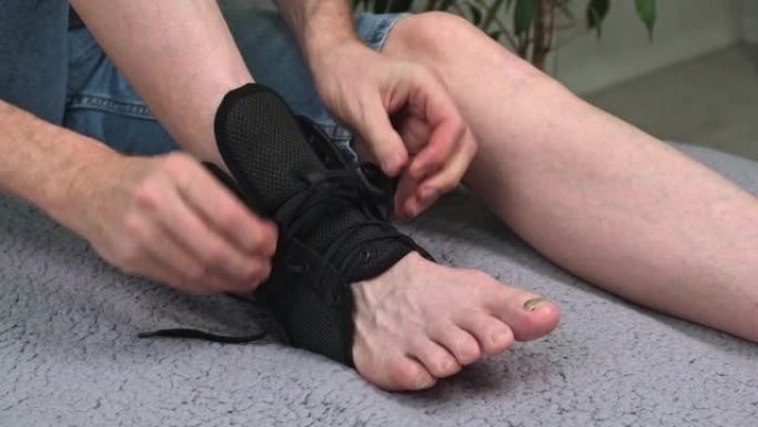 男子在脚踝关节区域的受伤腿上绑上特殊的固定绷带。特写