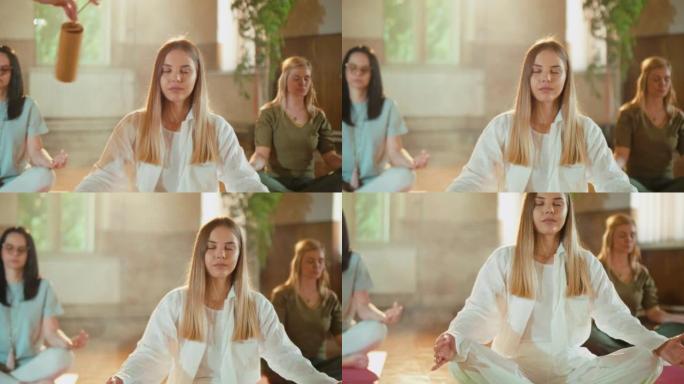 年轻女孩在集体瑜伽课上冥想，而教练用Kosi编钟发出悦耳的声音