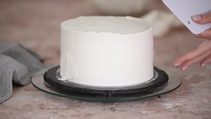 糕点女人在分层蛋糕上撒上奶油的特写。