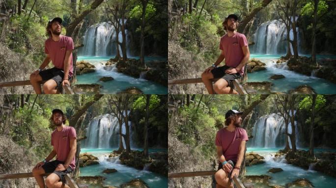 男子坐在墨西哥恰帕斯州El Chiflon瀑布附近的篱笆上