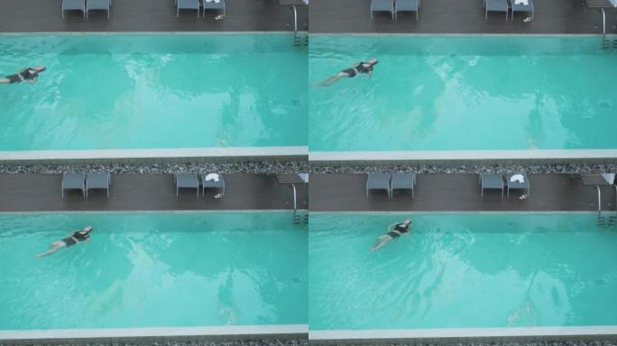 活跃的年轻女子在游泳池里潜水，泼水。在热带度假胜地放松的女士。穿着泳衣的女人跳着游泳池游泳