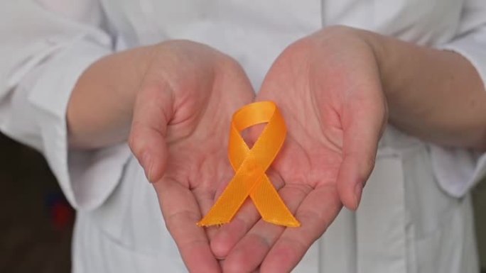 国际儿童癌症日。穿着白大褂的女医生拿着黄丝带。肉瘤意识，膀胱癌。白血病癌症意识。世界多发性硬化症日。