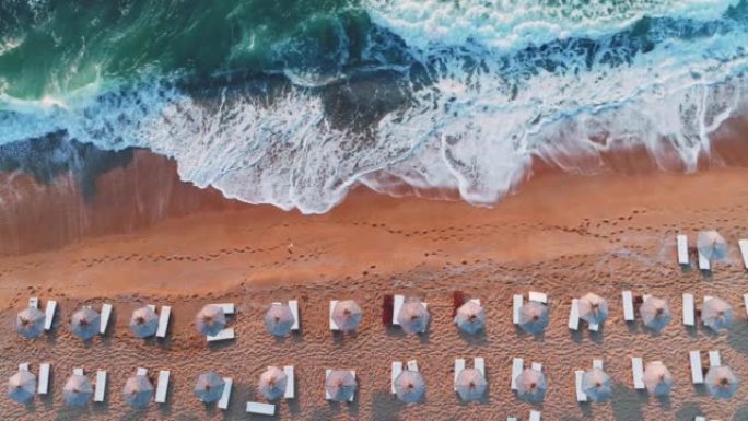 白伞和海浪冲刷沙滩的海滨鸟瞰图