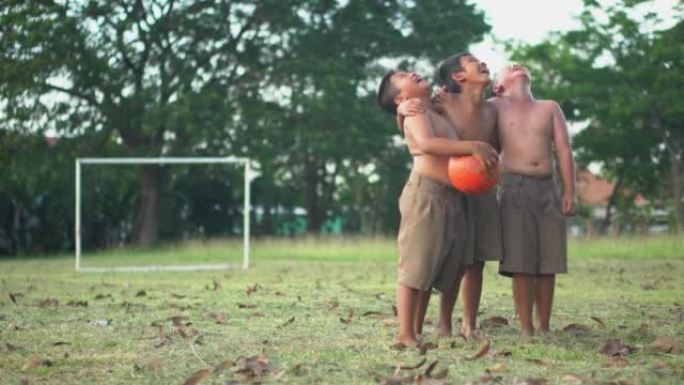 夏天阳光明媚的乡村，亚洲男孩朋友在绿色的草地上大笑。概念友谊和世界杯的比赛之路。