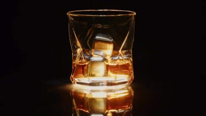 玻璃威士忌，黑色背景上有冰冷的石头，在镜子桌上旋转。