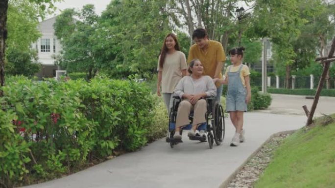 亚洲家庭与残疾的老年妇女坐在公园的轮椅上