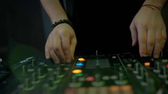 dj的手触摸按钮和滑块，使用混音控制器播放电子音乐，夜总会的摇摆派对。特写，慢动作